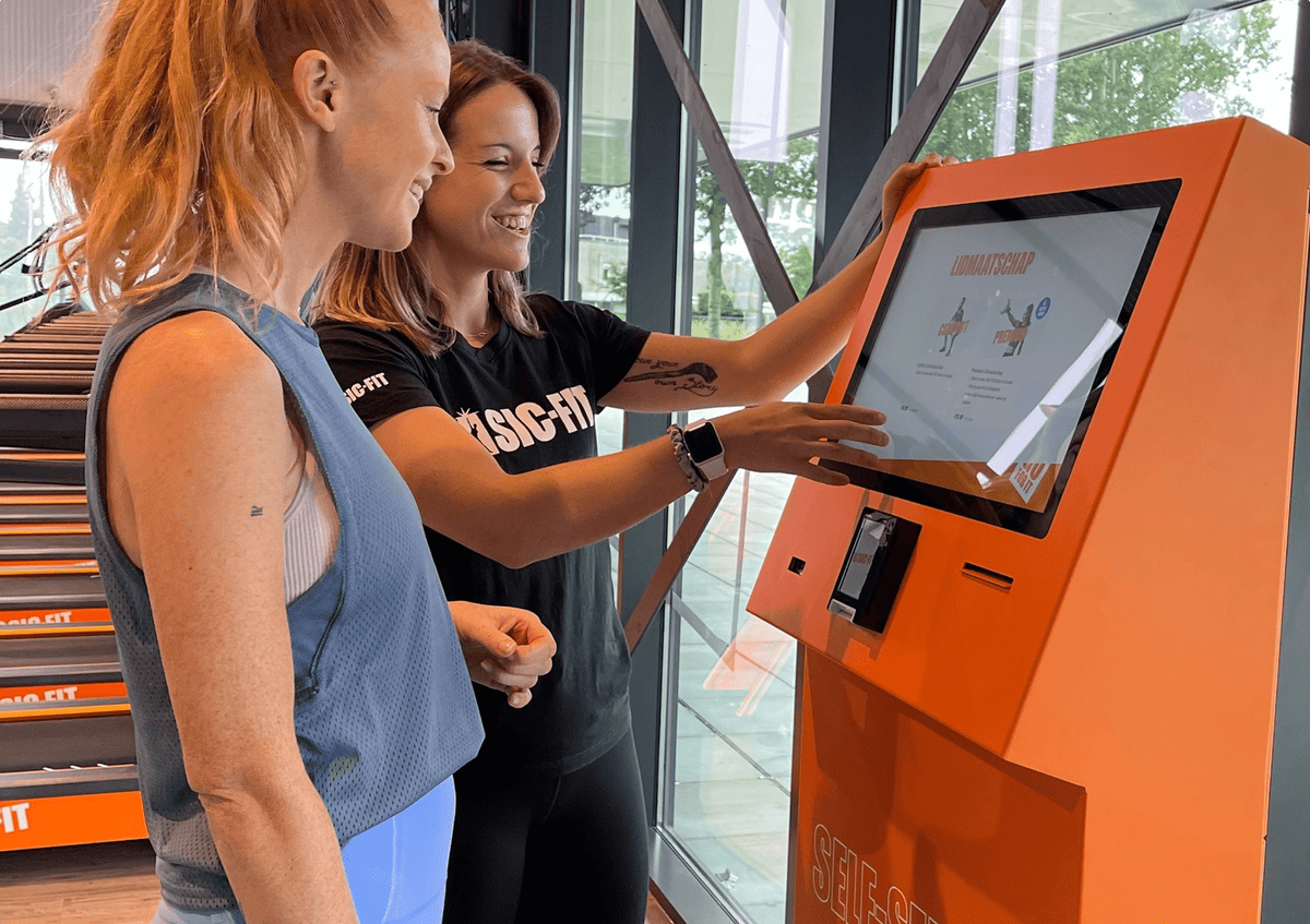Gym member using a Beetronics touchscreen at self check-in.