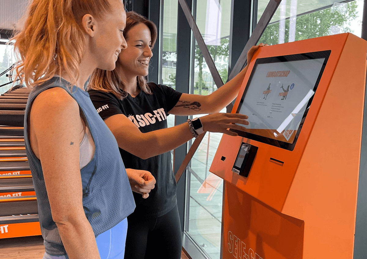 Gym member using a Beetronics touchscreen at self check-in.