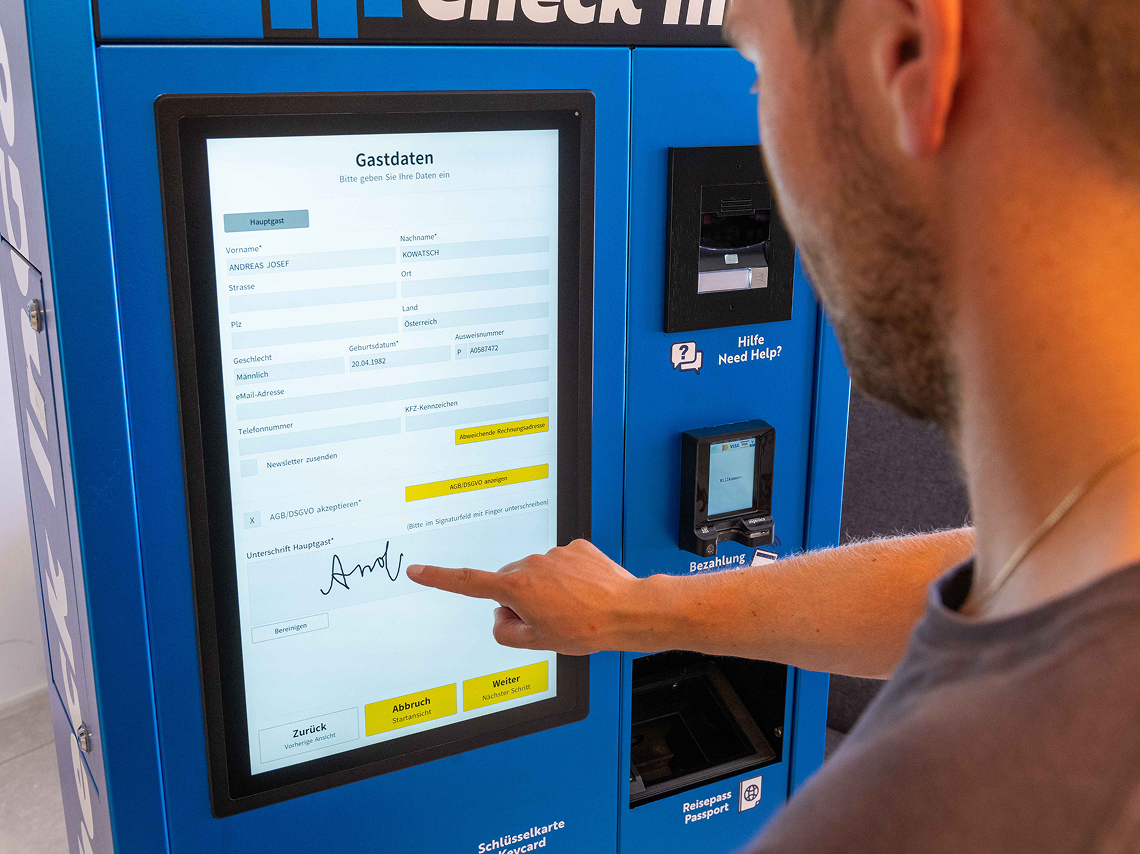 Guest completing digital registration on a Beetronics touchscreen hotel kiosk with passport scan and signature capture.