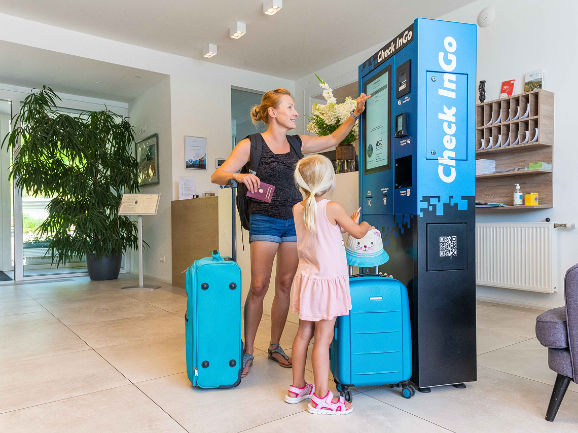 Check-InGo-03.png – Family using a Check-InGo self-service kiosk in a hotel lobby for fast, unattended check-in and room access.